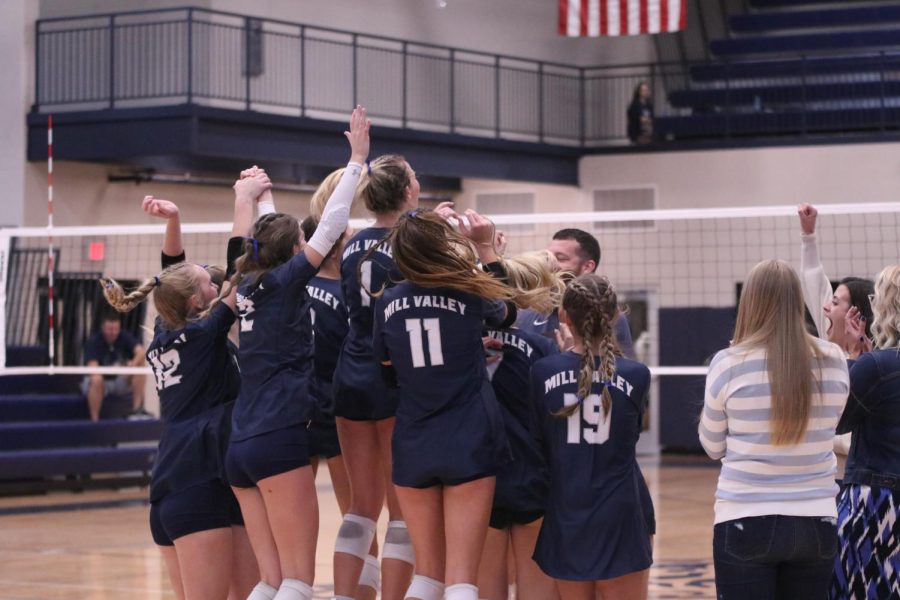 The team jumps into the air out of excitement while being given their trophy. 