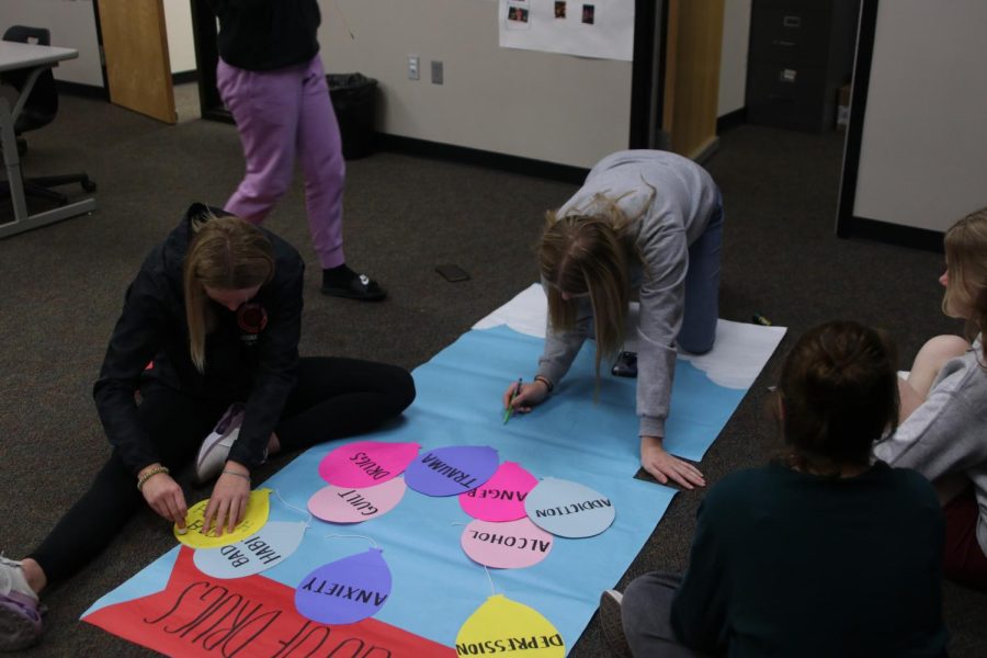 Sketching out on the paper, junior Jenna Graber and junior Ella Hansen put glue on a balloon on Tuesday, Oct 25. 