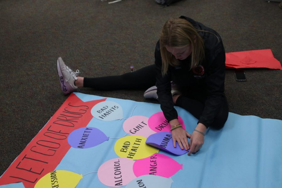 Junior Ella Hansen glues down the trauma balloon on the paper on Tuesday, Oct. 25.