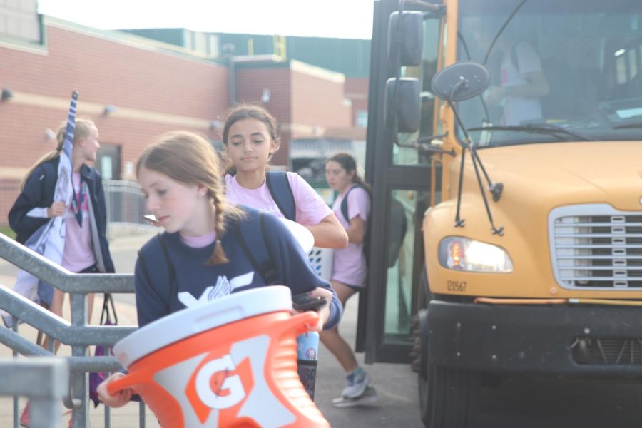 Freshman Elly Hayes carries a water cooler up the stairs followed by sophomore Alonnah Gage.