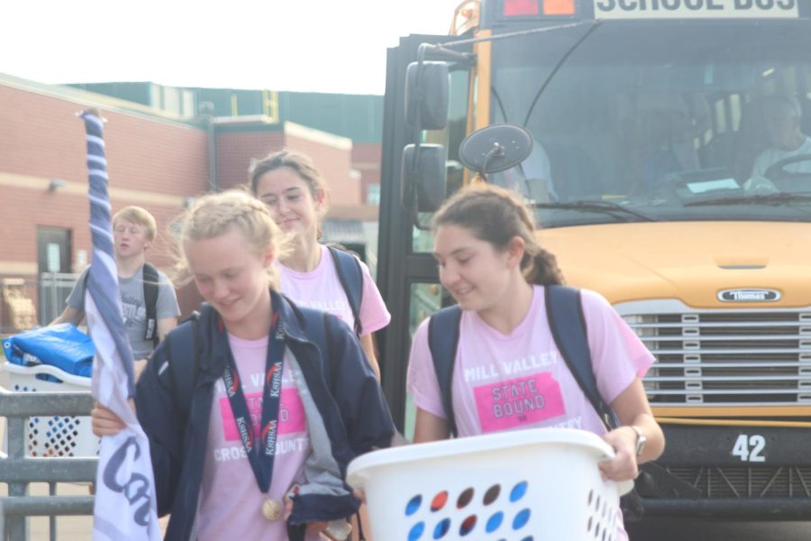 Smiling with one another, sophomore Charlotte Caldwell and junior Kynley Verdict carry supplies from the bus back into the school followed close behind by freshman Paige Roth.