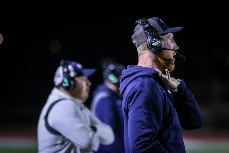 Talking into his headset, defensive coordinator coach Drew Hudgins communicates with the team on their next play.