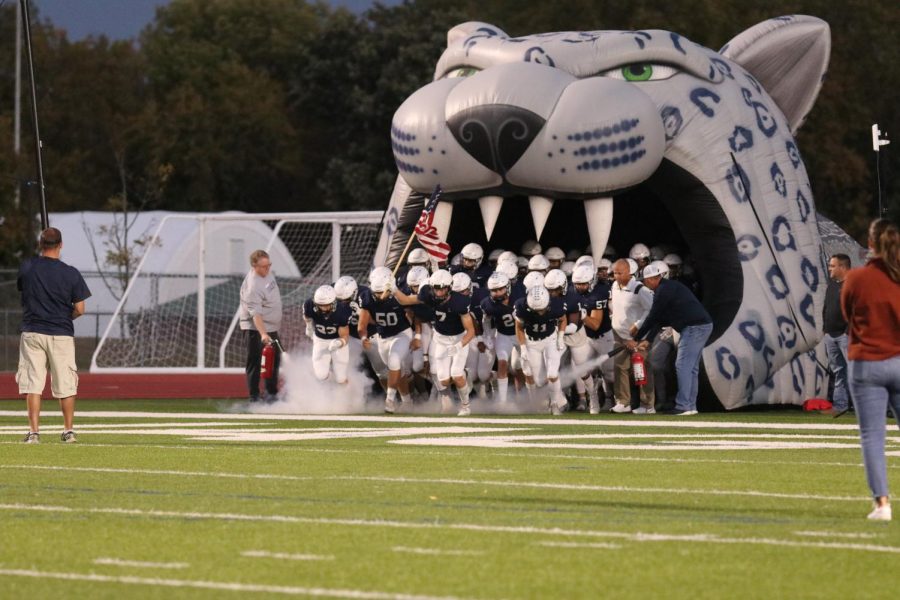 The football team leaves the Jaguar head and runs onto the field.  