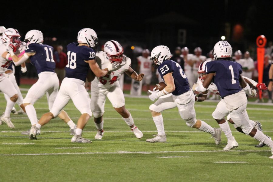 Clutching the ball, senior Holden Zigmant dodges Olathe North defense in an attempt to gain yardage on the play