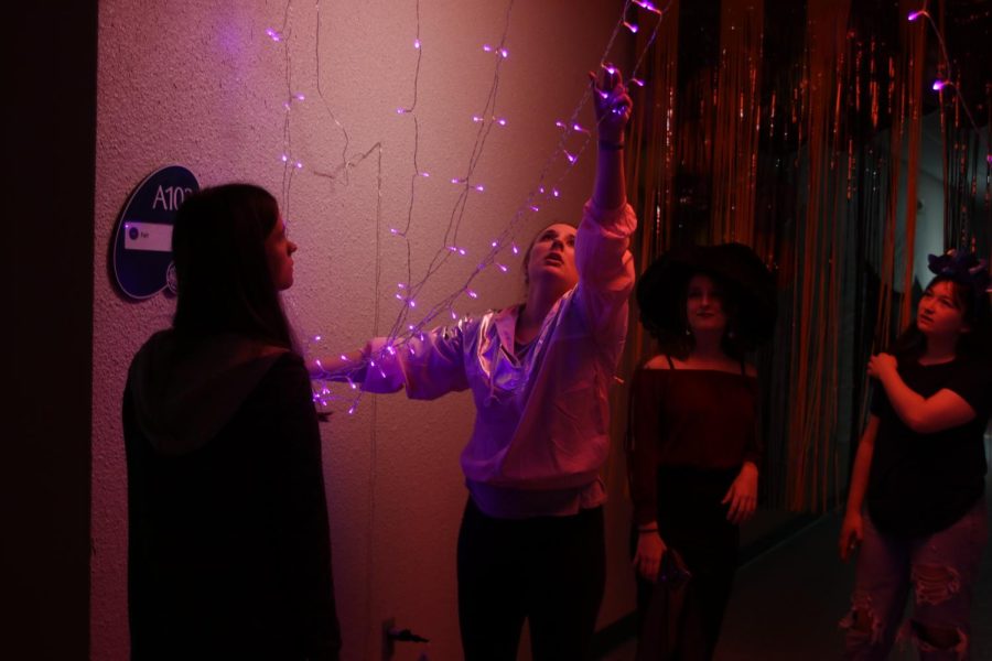 NEHS sponsor Page Anderson ties lights to the wall.
