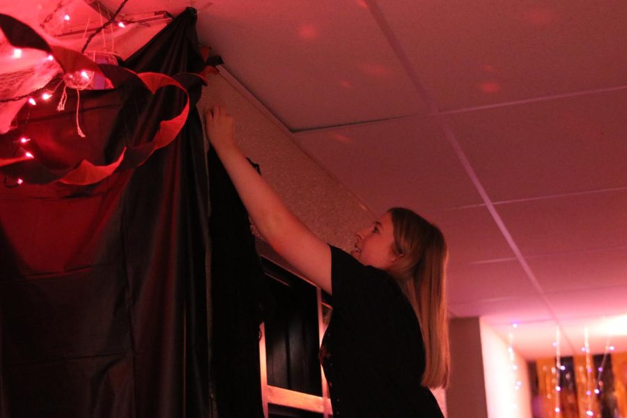 Senior Ashlyn Hogg hangs up a black spider web. 