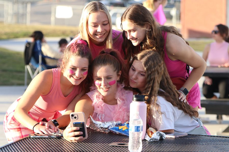 To give proof that they attended the tailgate, juniors Ellie Walker, Maddie Angell, Kaitlyn Burke and Abby Wolff huddle around junior Lucy Roy to take a picture. 