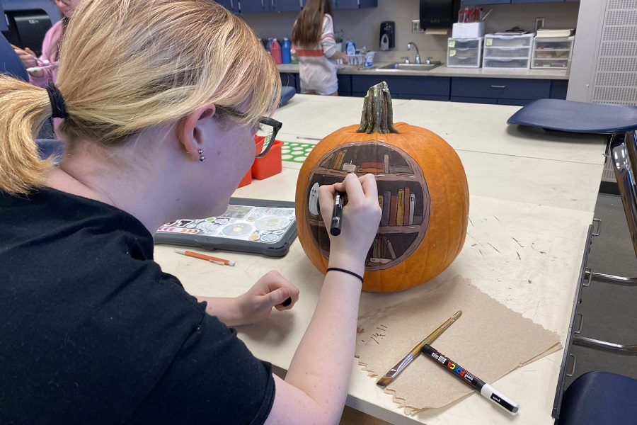 Junior Emma Clement paints a Halloween themed bookcase on her pumpkin for Pumpkin Palooza.