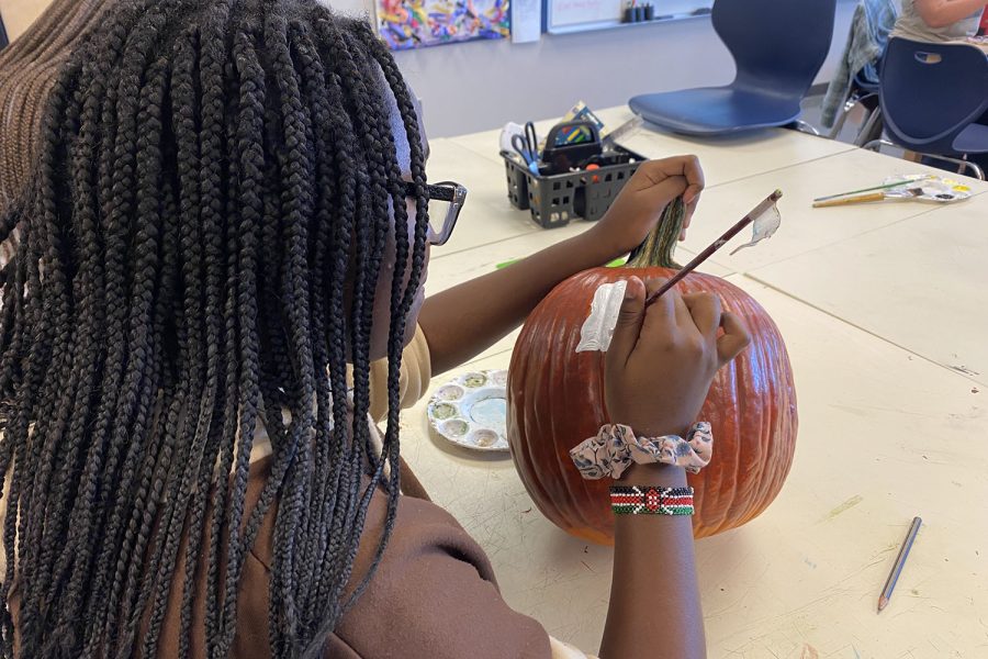 Freshman Doreen Mahugu begins painting a design on her pumpkin.