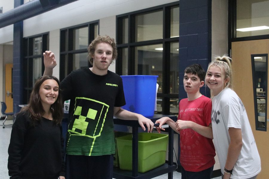 During seminar, junior Emma Hicks and Mia Reese alongside seniors Mikey Jobe and Jackson Stutheit stand outside the school lunchroom with recycling bins. The students helped with emptying recycle bins from B-hall Wednesday, Oct. 5. 