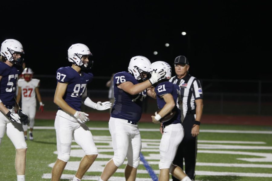 Celebrating a touchdown,  senior Jack Melvin holds on to junior Tristan Bakers helmet.