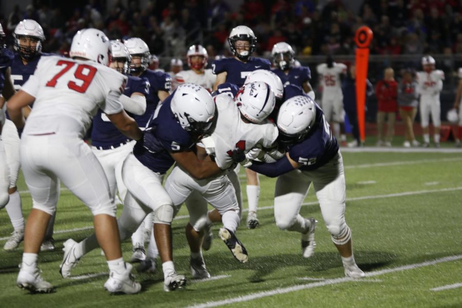 Sophomore Jayden Woods and seniors Broc Worcester and Grant Rutkowski team up to tackle the running back.