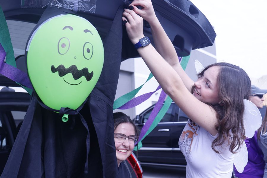 Reaching up, junior Bridgit Duffin sets up decorations for the Womens’ Empowerment Club’s Trunk at Pinnacle Gymnastics’ annual Trunk or Treat event Saturday, October 29. 