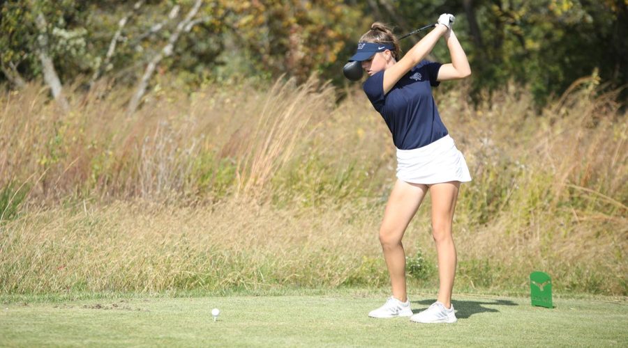 With arms held high, freshman Lola Dumler prepares to drive her ball down the fairway.
