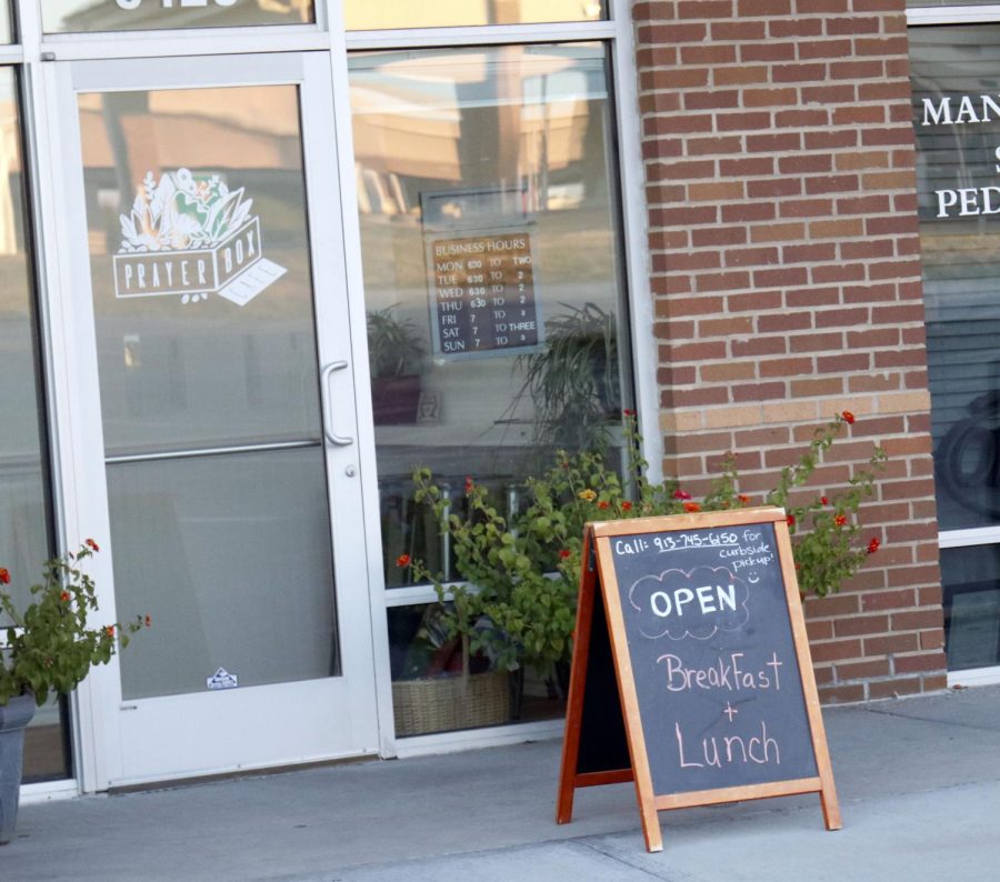 Featuring a chalkboard that holds information and occasionally seasonal items, the opening to Prayer Box Cafe shows shows the times the cafe is open.