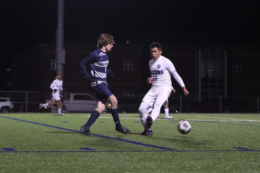 While he works around his opponent, senior Toby Kornis kicks the ball. 