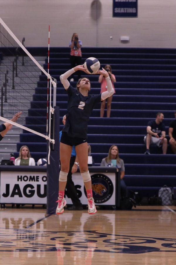 Feet off the ground, junior Ava Jones begins to set the ball to a hitter.