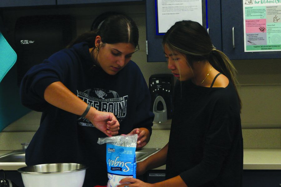 Seniors Amaiya Manirad and Torri Olivarez work together to measure ingredients for the cookie dough dip.