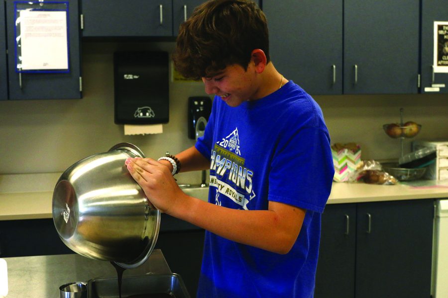 Working diligently, junior Corbin Garnand pours brownie batter into a pan.