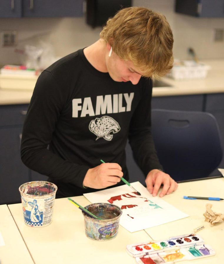 Working on his watercolor painting, freshman Cru Akins shades red and brown paint into his painting in Krystal Strong’s Art I class Friday, Sept.16.