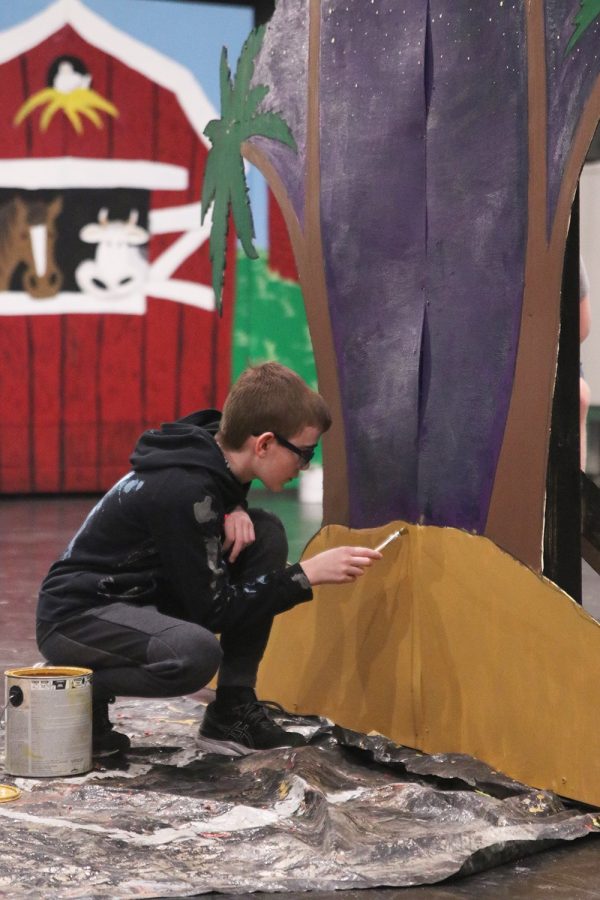 Separating the yellow sand from the dark purple night sky, freshman Ryan Cannata cleans up the edges on a desert-like set Saturday, Oct. 29. 