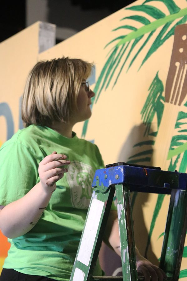 After adjusting the palm leaves to the edge of the set, junior Harley Quinn Boehm looks over her work Saturday, Oct. 29. 