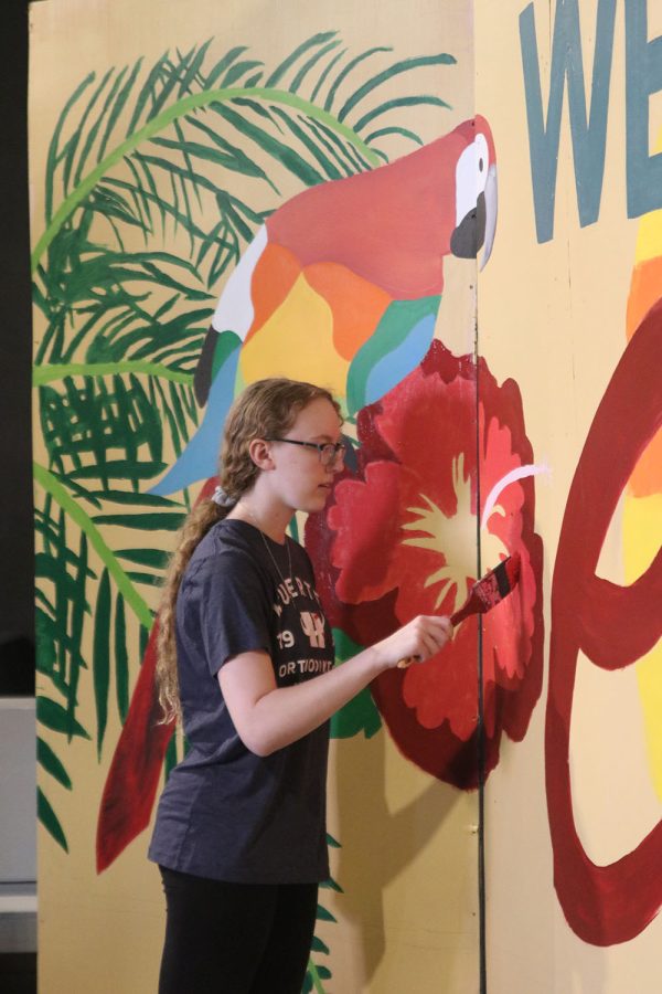 Adding another coat of red color onto a painting of a hibiscus flower, a freshman student volunteers her time to help with the “Welcome to Cuba” set Saturday Oct. 29. 