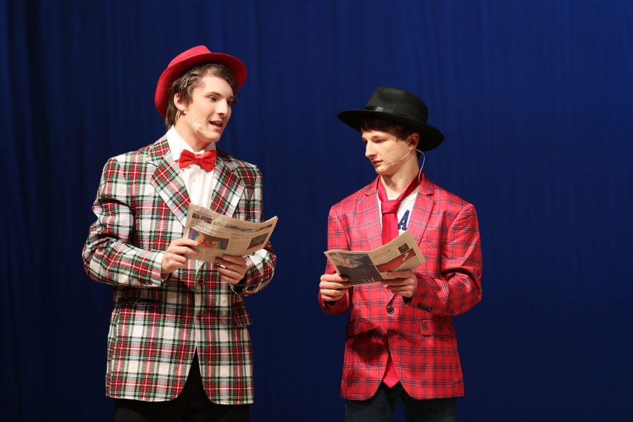 Newspapers in hand, sophomore Ayden Brown and freshman Drew Cormany converse on stage.