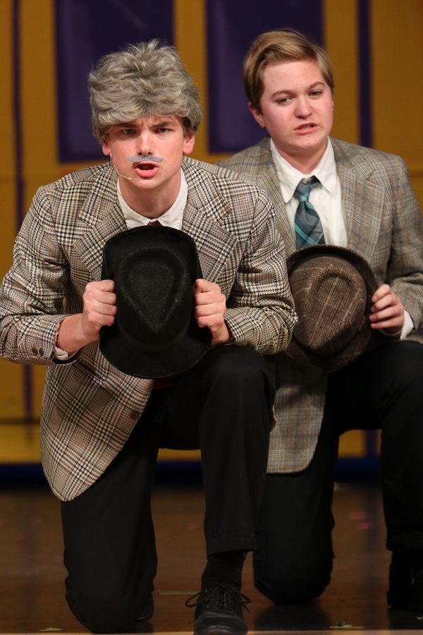 Kneeling on stage, senior Finn Campbell and freshman Evan LeRoy look out to the audience. 