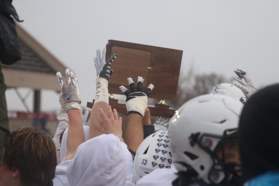 Players hold up a four in front of the newest state trophy.