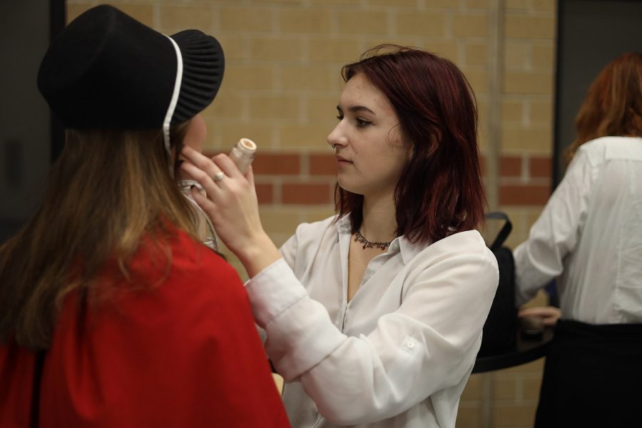 Before the show, sophomore Riley Urban helps another cast member with their makeup.