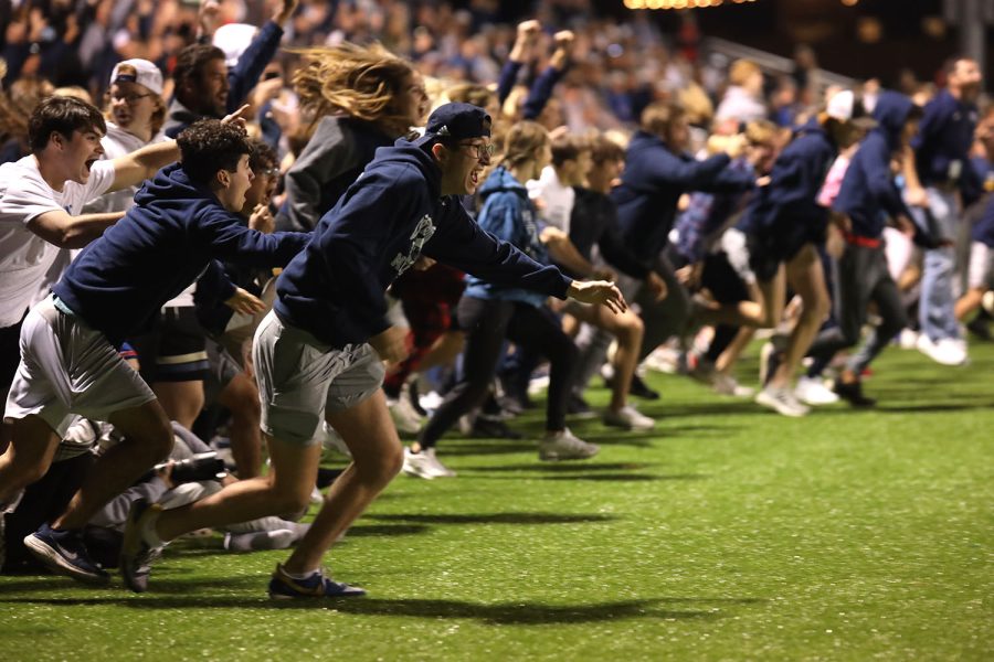 On the sideline, senior Max Weber rushes onto the field with the rest of the student section after the team won. 