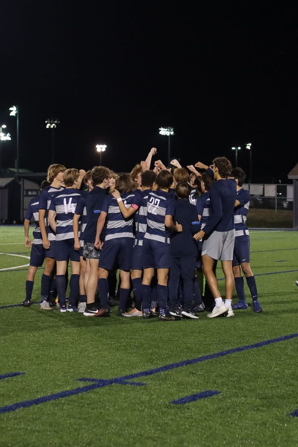 Huddled together in the middle of the field, the team celebrates after their win. 
