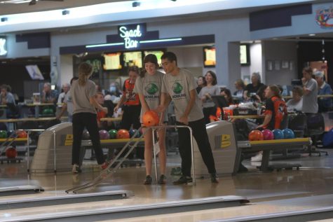 Aiming for the pins, sophomore Boji Green rolls the ball down the ramp with help from senior Jane McDaneld.