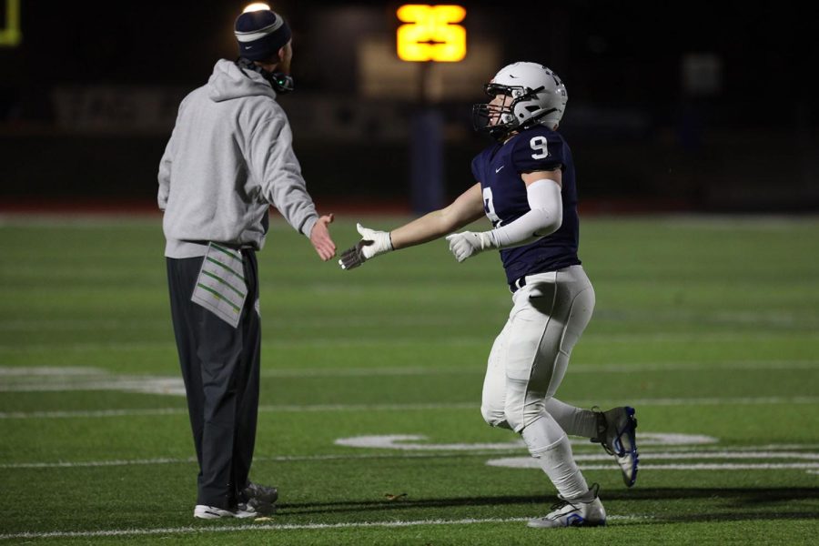 Encouraging his player for a good play, offensive coordinator Drew Hudgins high fives senior Noah Coy. 