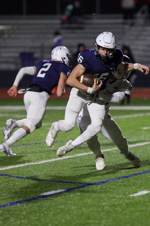 Carrying the ball, sophomore Connor Bohon gets tackled by a Pittsburg player.