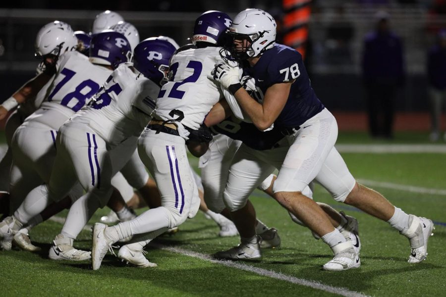 Holding the opposing line, junior Gus Hawkins pushes against the defensive lineman. 