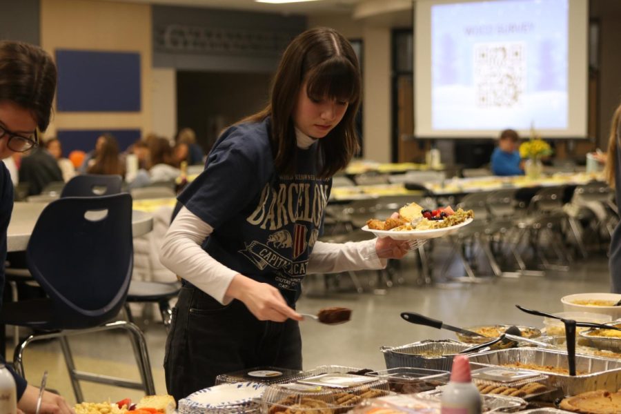 Plate in hand, senior Sarah Johnston gets some food from the desert table