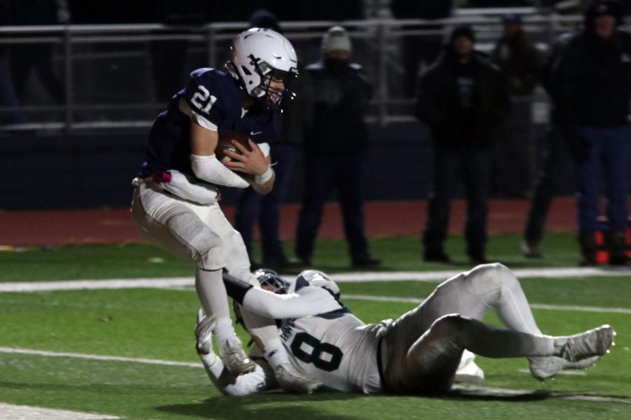 Junior Tristan Baker holds onto the ball while being tackled.
