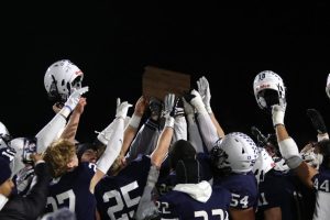 The football players hold their arms and helmets up in the air after receiving the 5A sub-state trophy for their 63-0 blowout over Blue Valley Southwest Friday, Nov. 18.