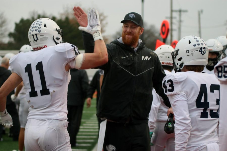 Coach Andrew Hudgins gives senior Mark Bauer a high five during the last few seconds of the game.