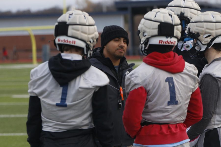 Talking during a water break, running backs coach Cruz Gallegos makes jokes with the players.