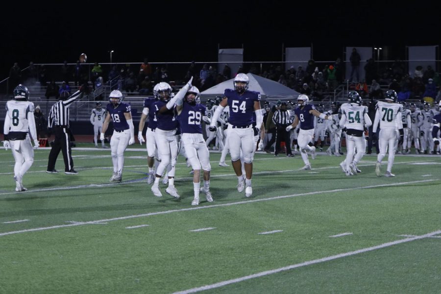 Celebrating with the infamous land shark move, senior Dylan Massey gets the sideline excited after a big tackle. 