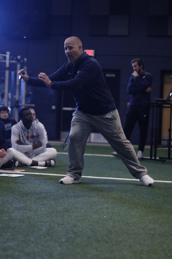 Demonstrating a move to the linemen, coach Joel Applebee shows how he wants his players to move.