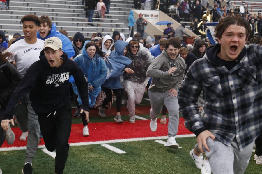 Storming the field, students yell as they charge toward the team.