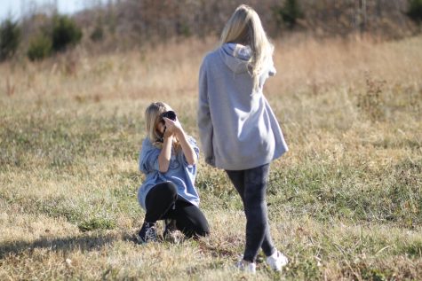 Kneeling down for a better angle, freshman Eden Christain takes pictures of her sister on Tuesday, Nov. 1.