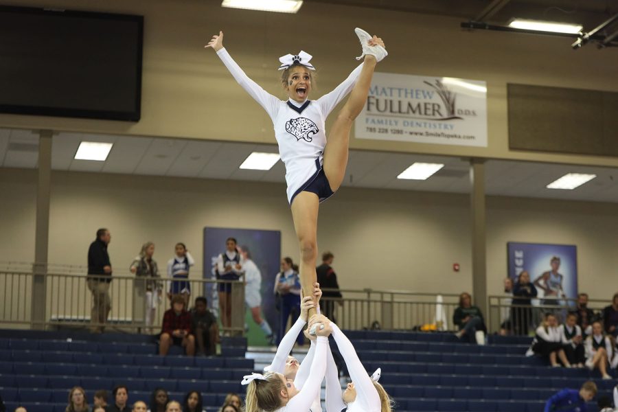 With a big smile on her face, sophomore Jada Winfrey waves to the crowd while doing a heel stretch.