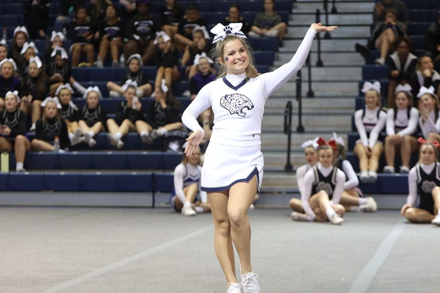 Waving to the crowd, sophomore Joey Nightingale spirits before doing her jumps.