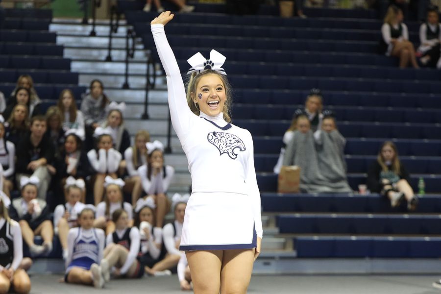 Hand in the air, junior Maci Burger waves with a smile on her face.