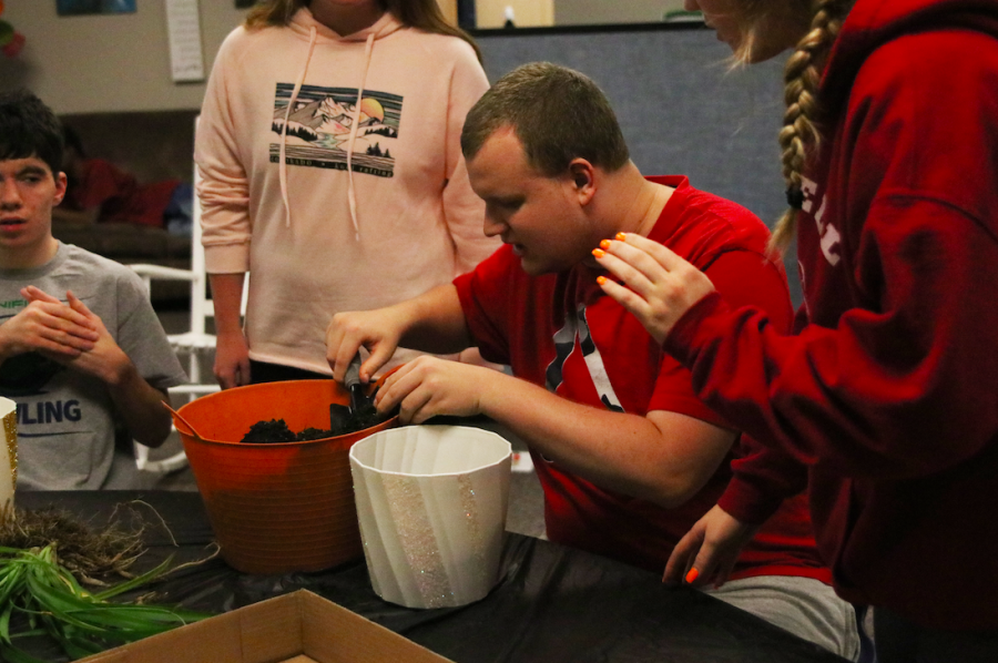 Adjusting the amount of soil, junior Gus Gosch removes dirt from a pot with the helps of his peers Wednesday, Oct. 26.
